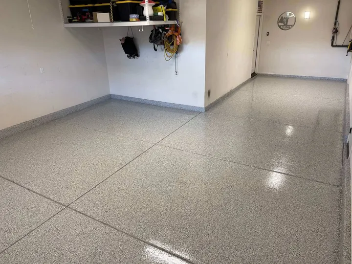 Gray flake garage floor with a glossy polyaspartic topcoat and cove base